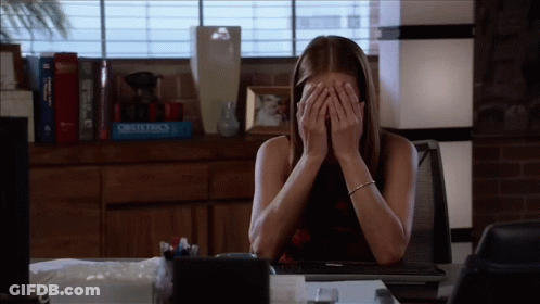 Woman Covering Face At Desk With Obstetrics Book GIF