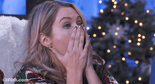 Woman Covering Mouth With Hands At Christmas Tree GIF