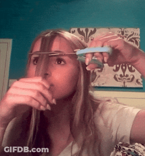 Woman Cutting Hair In Front Of Blue Wall GIF