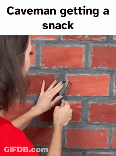 Woman Cutting Hole In Brick Wall With Scissors Caveman Getting A Snack GIF