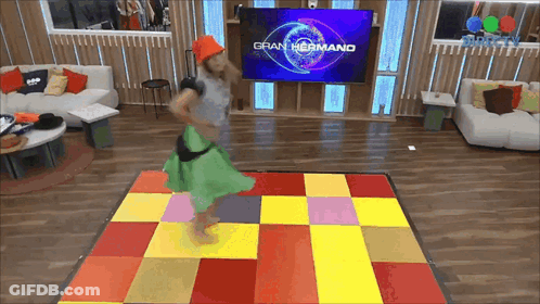 Woman Dancing In Front Of Gran Hermano TV Screen GIF