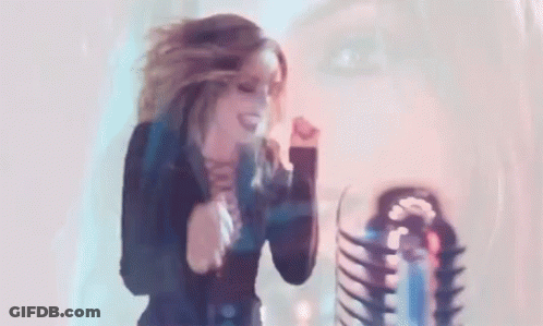 Woman Dancing In Front Of Microphone With Skeleton In Background GIF