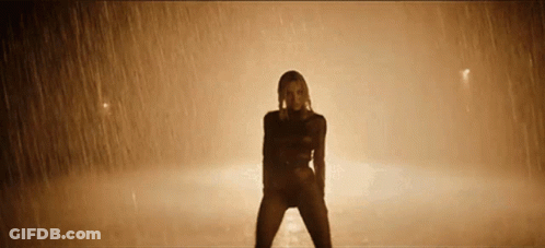 Woman Dancing In Rain In Dimly Lit Room GIF
