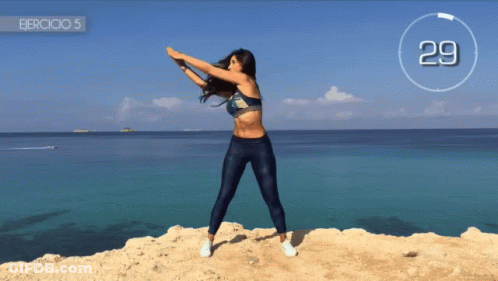 Woman Doing Exercises On Cliff Near Ocean 29 GIF