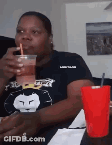 Woman Drinking From Plastic Cup With Straw Sitting At Table GIF