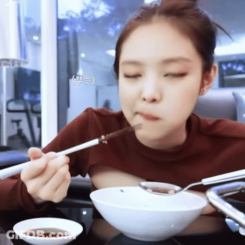 Woman Eating Bowl Of Food With Chopsticks And Spoon GIF