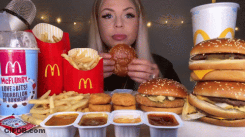 Woman Eating Hamburger Beside McDonald's McFlurry Cup GIF