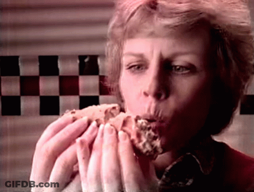 Woman Eating Hamburger In Front Of Checkerboard Wall GIF