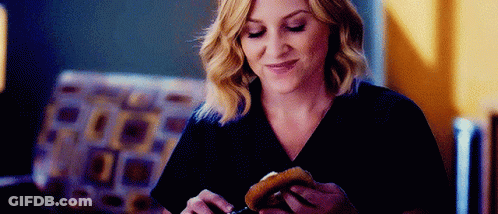 Woman Eating Hamburger In Living Room GIF