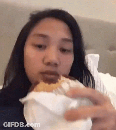 Woman Eating Hamburger On Bed GIF