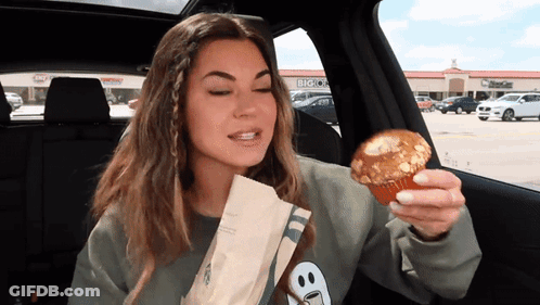Woman Eating Muffin In Car With Big O's Background GIF