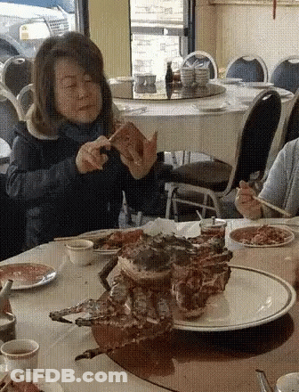 Woman Eating Sandwich At Restaurant Table GIF