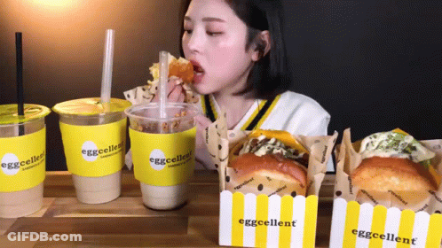 Woman Eating Sandwich Drinking From Eggcellent Cup GIF