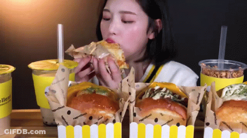 Woman Eating Sandwich With Ingredients On Wrapper GIF
