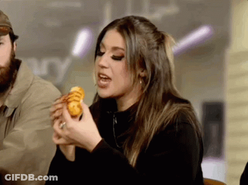 Woman Eating Sandwich With Man Behind Her GIF