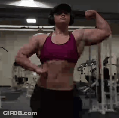 Woman Flexing Muscles In Gym With Headphones And Hat GIF