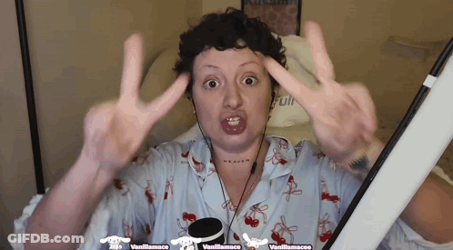 Woman Giving Peace Sign In Front Of Vanillamacaco Sign GIF