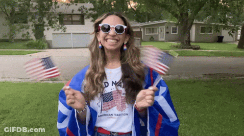 Woman Holding American Flags In American Tradition Shirt GIF