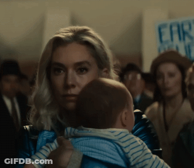 Woman Holding Baby In Front Of Far Right Sign GIF