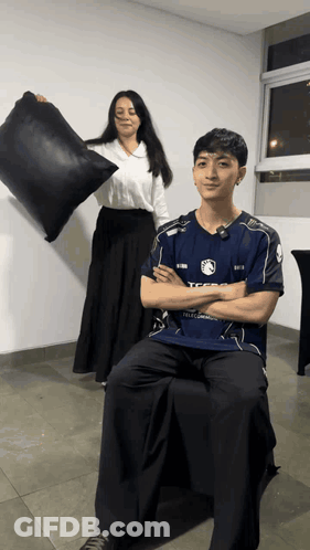 Woman Holding Black Pillow In Front Of Man In TFSG Shirt GIF