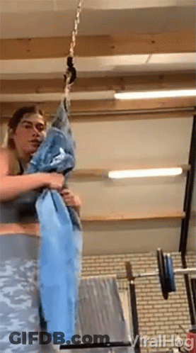 Woman Holding Blue Towel Hanging From Chain In Gym GIF