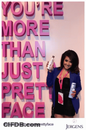 Woman Holding Bottle In Front Of Sign You're More Than Just Pretty Face GIF