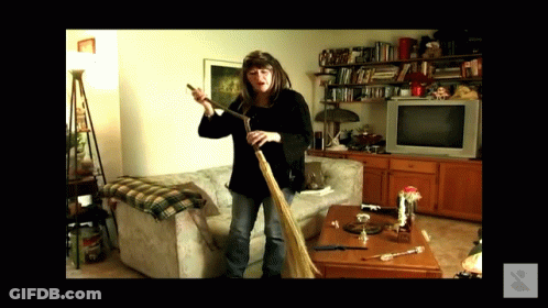 Woman Holding Broom In Living Room With TV GIF