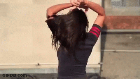 Woman Holding Her Hair In Front Of Building GIF