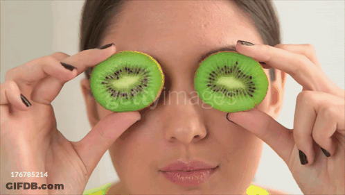 Woman Holding Kiwi Slices In Front Of Eyes GIF