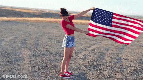 Woman Holding Large American Flag In Dirt GIF