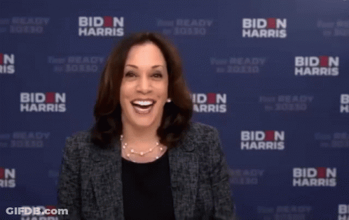 Woman Holding Leg In Front Of Biden Harris Banner GIF