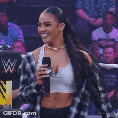 Woman Holding Microphone Before Crowd In Crop Top And Plaid Jacket GIF