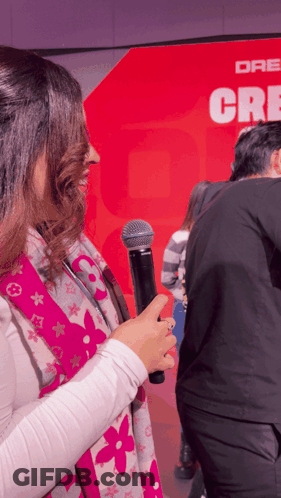 Woman Holding Microphone Before Red Wall Dr. Cre GIF