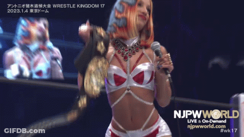 Woman Holding Microphone In Front Of NJPW World Sign GIF