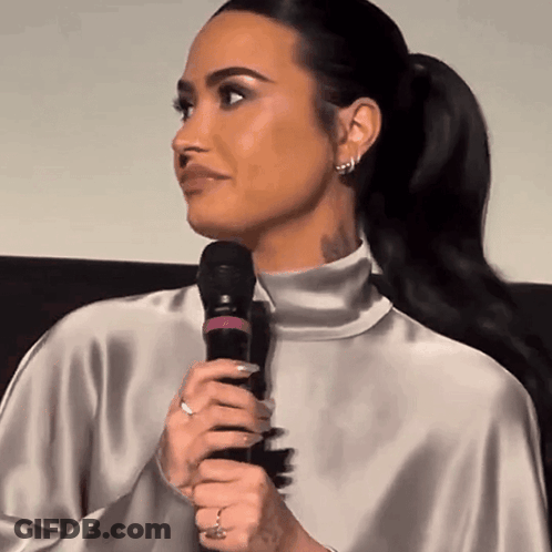 Woman Holding Microphone In Silver Top GIF