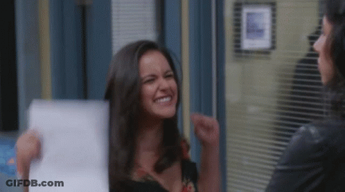 Woman Holding Paper Smiling While Another Laughs GIF