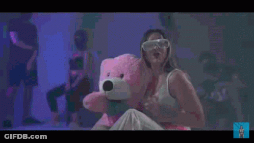 Woman Holding Pink Teddy Bear In Front Of Crowd GIF