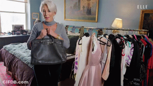 Woman Holding Purse In Front Of Clothes Rack GIF