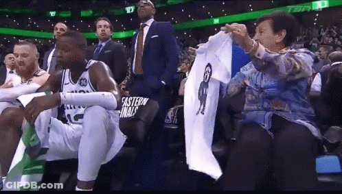 Woman Holding Shirt With Man Picture While Basketball Player Sits In Stands GIF