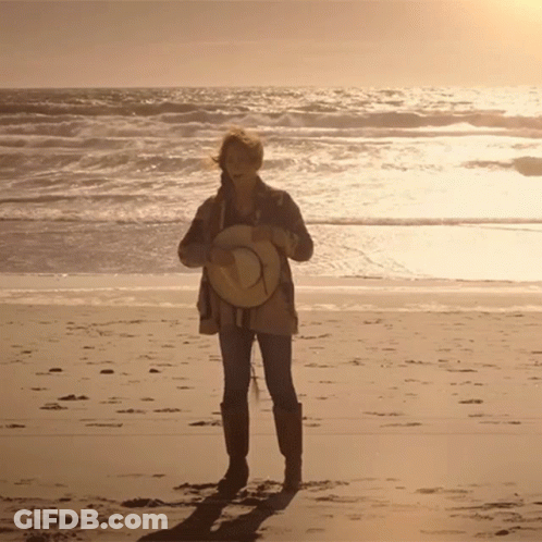 Woman Holding Straw Hat On Beach GIF