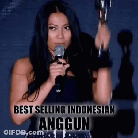 Woman Holding Trophy And Microphone In Front Of Best Selling Indonesian Anggun Sign GIF