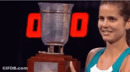 Woman Holding Trophy In Front Of 00 Sign GIF