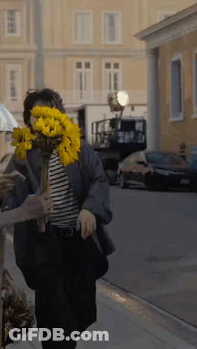 Woman Holding Yellow Flowers Behind Face GIF