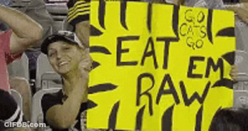 Woman Holding Yellow Sign Saying Eat Em Raw GIF