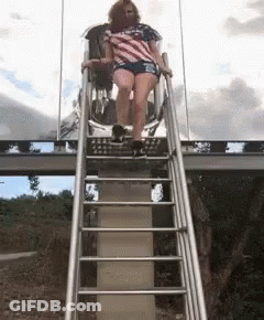 Woman In American Flag Shirt Sitting On Slide GIF