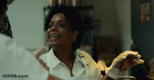 Woman In Apron And Gloves Smiling At Another Woman GIF