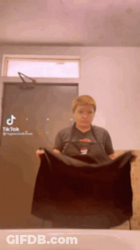 Woman In Apron Holding Black Towel GIF