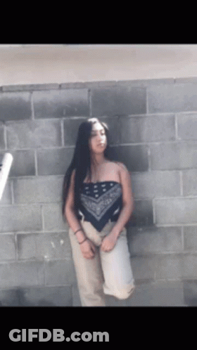 Woman In Bandana Top In Front Of Brick Wall GIF