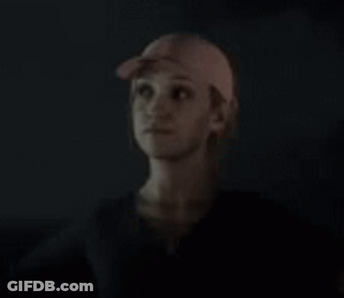 Woman In Baseball Cap Looking Up In Dark GIF