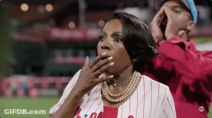 Woman In Baseball Uniform Covering Mouth While Man Shouts GIF